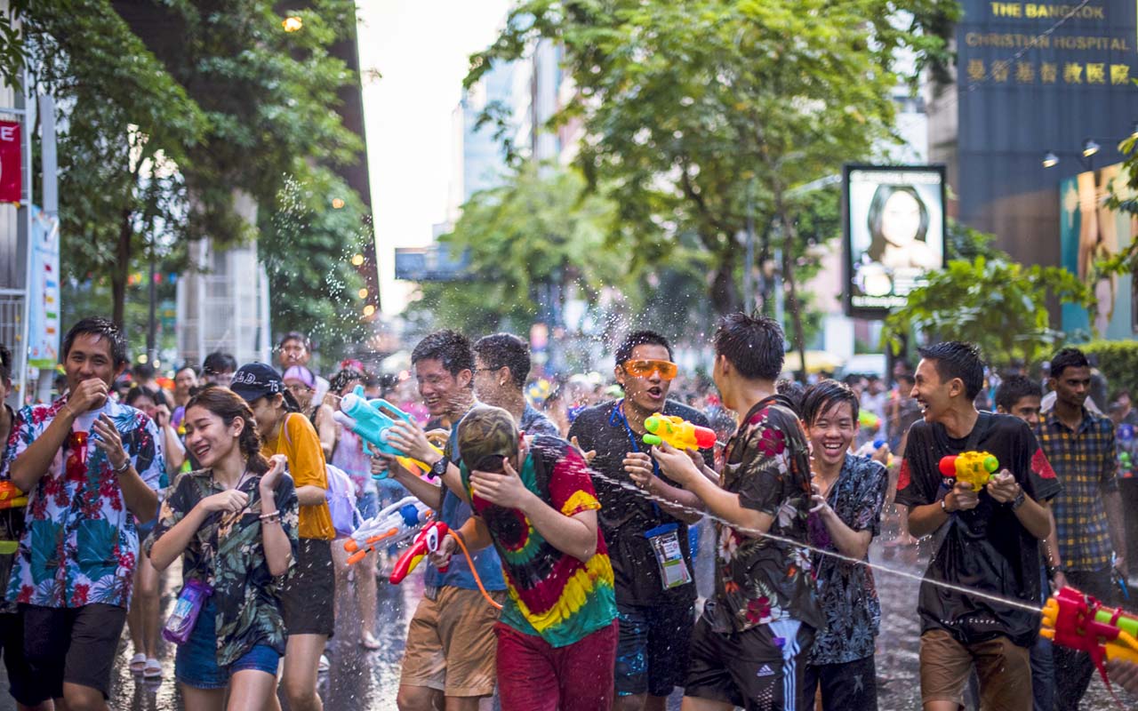 People celebrating Songkran Festival in Thailand with water guns on a busy street