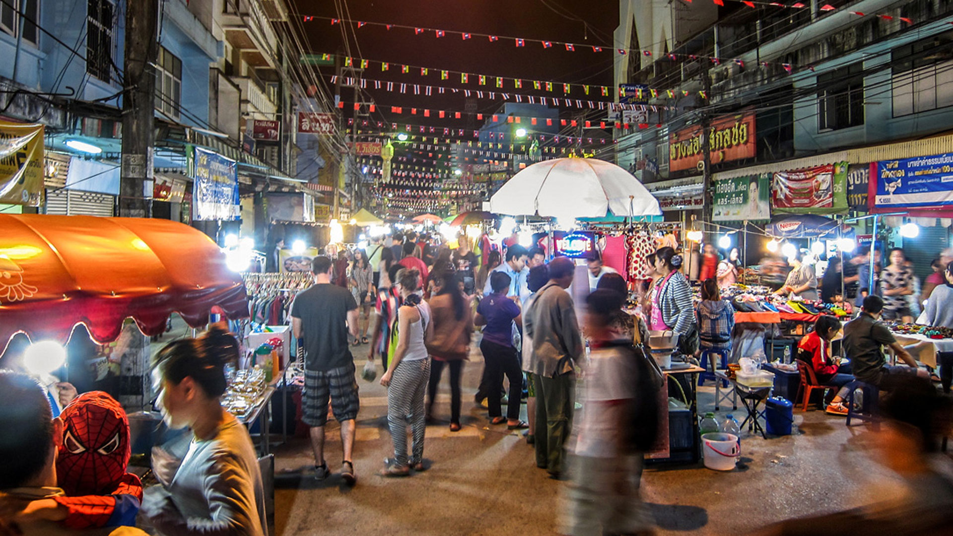A colorful night market with food vendors and shoppers